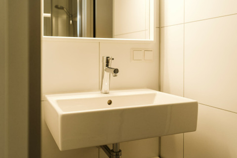 Lavabo moderne avec miroir et mur carrelé au Kleproos, lodge du parc De Klepperstee aux Pays-Bas.