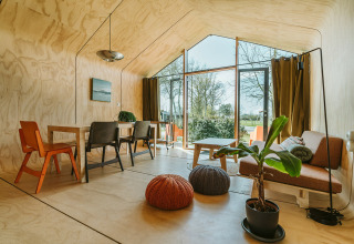 Interior luminoso de la casa Oep en el parque De Klepperstee, Países Bajos, con grandes ventanales y plantas.