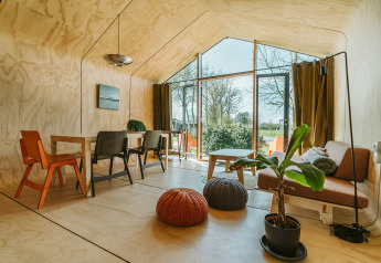 Licht interieur van het Oep natuurhuisje in Vakantiepark De Klepperstee, met grote ramen en moderne meubels.
