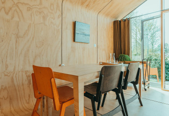 Eethoek met houten wanden en moderne stoelen in Oep, een natuurhuisje op vakantiepark De Klepperstee, Nederland.
