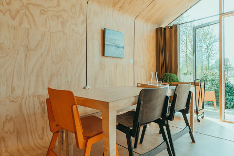 Comedor con paredes de madera y sillas modernas en Oep, una casa natural en el parque De Klepperstee, Países Bajos.