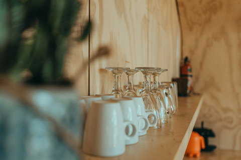 Shelf with glasses and mugs in a nature house at Holiday park De Klepperstee in the Netherlands, blurred foreground.