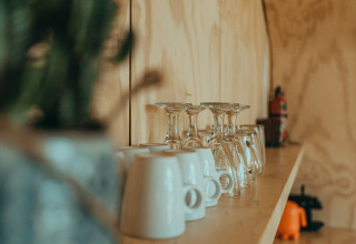 Plank met glazen en mokken in een natuurhuisje op vakantiepark De Klepperstee in Nederland, wazige voorgrond.