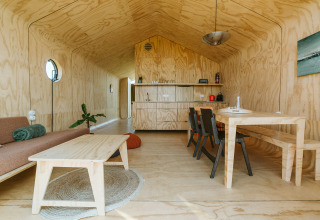 Vista interior de Oep, una casa de naturaleza en el parque De Klepperstee, Países Bajos, con muebles de madera.