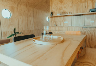 Interior de madera clara de casa de vacaciones con mesa, bandeja, jarra y vasos, Oep, De Klepperstee, Países Bajos.