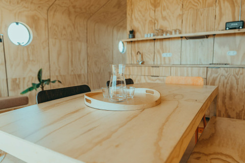 Interior de madera clara de casa de vacaciones con mesa, bandeja, jarra y vasos, Oep, De Klepperstee, Países Bajos.