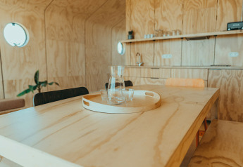 Interior de madera clara de casa de vacaciones con mesa, bandeja, jarra y vasos, Oep, De Klepperstee, Países Bajos.