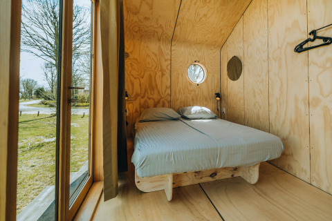 Slaapkamer met tweepersoonsbed en houten interieur in Oep natuurhuis, bij De Klepperstee, Nederland.