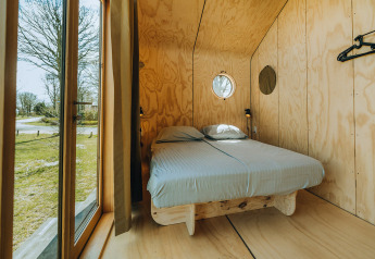 Slaapkamer met tweepersoonsbed en houten interieur in Oep natuurhuis, bij De Klepperstee, Nederland.