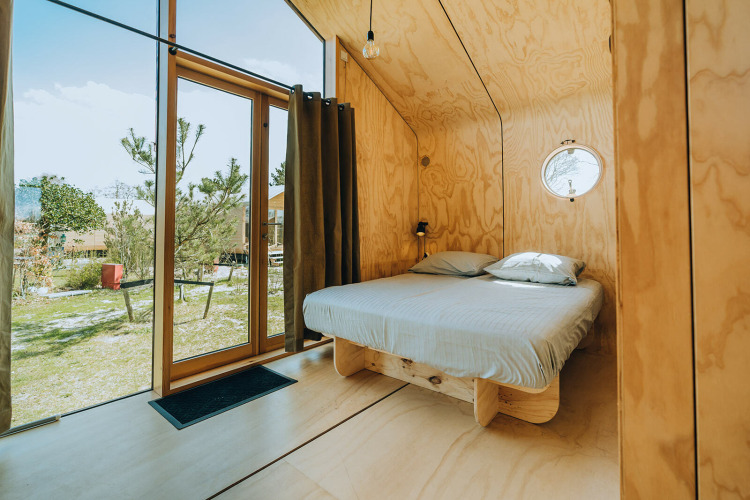 Dormitorio moderno de madera con cama doble y grandes ventanales en Oep, parque De Klepperstee, Países Bajos.
