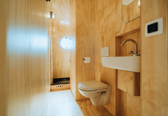 Moderne badkamer met houten lambrisering, hangtoilet en wastafel in Oep, Nature house, De Klepperstee, Nederland.