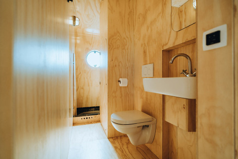 Baño moderno con paredes de madera, inodoro suspendido y lavabo en Oep, Nature house, De Klepperstee, Países Bajos.