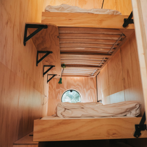 Literas de madera con sábanas blancas en una cabaña de Oep, Nature house, en De Klepperstee, Países Bajos.