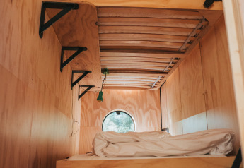 Literas de madera con sábanas blancas en una cabaña de Oep, Nature house, en De Klepperstee, Países Bajos.