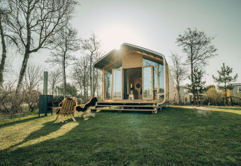 Maison nature Wikkelhouse Bear au parc de vacances De Klepperstee, Pays-Bas, entourée d’arbres et d’une pelouse.