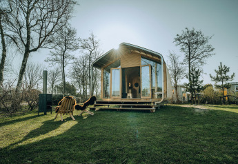 Wikkelhouse Bear natuurhuis in vakantiepark De Klepperstee, Nederland, omringd door bomen en gazon.