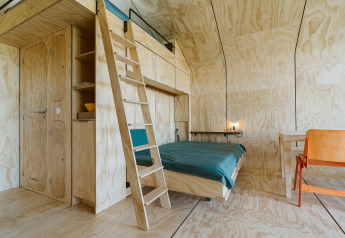 Modern natuurhuis interieur met houten panelen, vide, bed en bureau bij Wikkelhouse Bear, De Klepperstee.