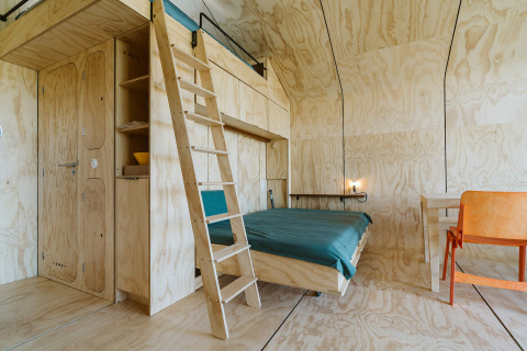 Interno di moderna casa nella natura con pannelli in legno, soppalco, letto e scrivania al Wikkelhouse Bear, De Klepperstee.