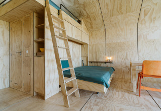 Interno di moderna casa nella natura con pannelli in legno, soppalco, letto e scrivania al Wikkelhouse Bear, De Klepperstee.