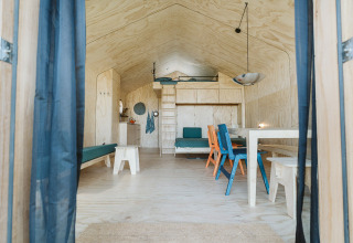 Vista interior de Wikkelhouse Bear en De Klepperstee, Países Bajos, con madera clara y sillas coloridas.