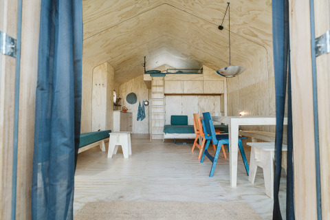 Interieur van Wikkelhouse Bear bij De Klepperstee, Nederland, met lichte houten wanden en kleurrijke stoelen.