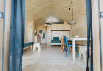 Innenansicht von Wikkelhouse Bear im De Klepperstee, Niederlande, mit hellem Holz und bunten Stühlen.