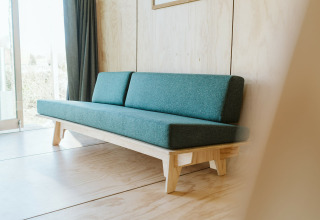 Minimalistische groene zetel in Wikkelhouse Bear, een natuurhuisje op vakantiepark De Klepperstee, Nederland.