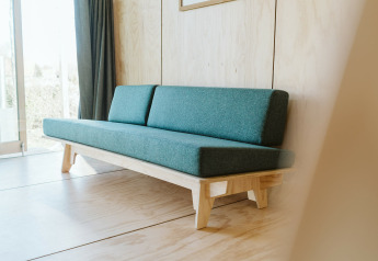 Sofá verde minimalista en Wikkelhouse Bear, una casa natural en el parque vacacional De Klepperstee, Países Bajos.