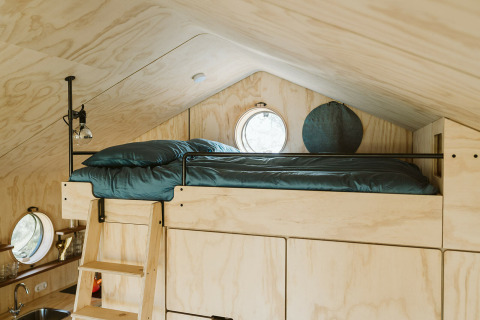 Lit en mezzanine avec draps verts dans Wikkelhouse Bear, maison nature du parc De Klepperstee, Pays-Bas.