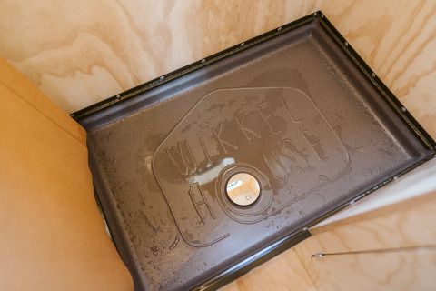 Binnenaanzicht van een douche met 'Wikkel House' in het water geschreven, Wikkelhouse Bear, Nederland.