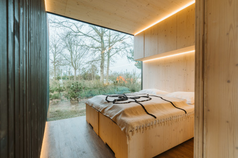 Bedroom in Ark Shelter nature house at De Klepperstee Holiday Park, Netherlands, with a forest view.