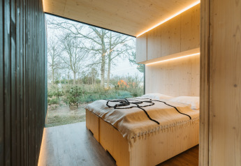 Schlafzimmer im Ark Shelter Naturhaus im Ferienpark De Klepperstee, Niederlande, mit Waldblick.