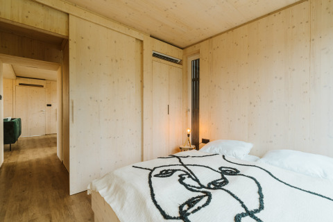 Dormitorio minimalista con paredes de madera en Ark Shelter, casa de naturaleza en De Klepperstee, Países Bajos.