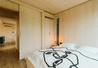 Minimalistische houten slaapkamer in Ark Shelter, een natuurhuisje in vakantiepark De Klepperstee, Nederland.