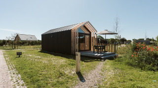 Tiny house moderna al parco vacanze De Klepperstee nei Paesi Bassi con terrazza e tavolo esterno.