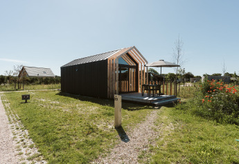 Moderne tiny house bij vakantiepark De Klepperstee in Nederland met terras en tuinmeubilair.