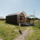 Moderne tiny house bij vakantiepark De Klepperstee in Nederland met terras en tuinmeubilair.