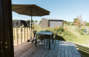 Wooden deck with table, four chairs and umbrella outside a tiny house at De Klepperstee, Netherlands, sunny day.
