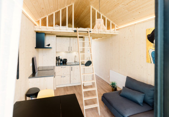Modernes Tiny House mit mezzanine, Küche, Leiter und Sofa im Ferienpark De Klepperstee in den Niederlanden.