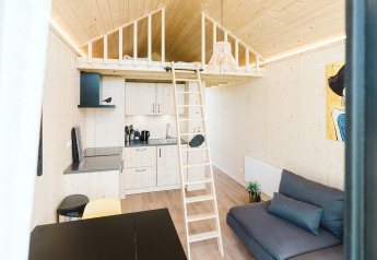 Lichte, moderne tiny house met een loft, kitchenette, ladder en bank op vakantiepark De Klepperstee in Nederland.