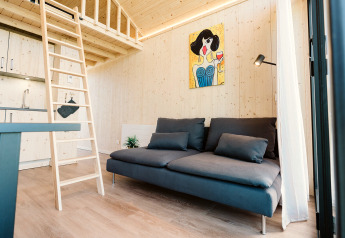 Helles, modernes Wohnzimmer eines Tiny Houses im Holiday park De Klepperstee, Niederlande, mit Sofa und Hochbett.