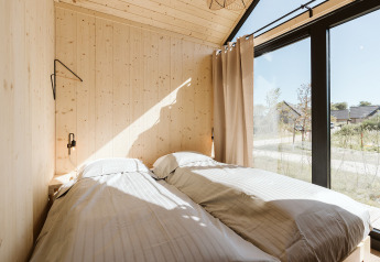 Zonnige slaapkamer in tiny house Stulp op vakantiepark De Klepperstee, met grote ramen en houten wanden.