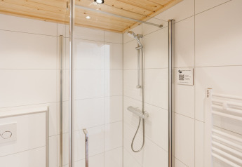 Moderne douche in compacte badkamer met witte tegels bij Stulp tiny house in De Klepperstee, Nederland.