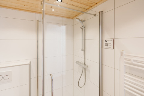 Ducha moderna en un baño compacto con azulejos blancos en Stulp, tiny house de De Klepperstee, Países Bajos.