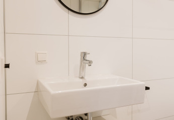 Modern white sink with mirror in a tiny house bathroom at Stulp, Holiday park De Klepperstee, Netherlands.
