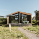 A modern nature house with large glass windows and wooden deck at Holiday park De Klepperstee, Netherlands.