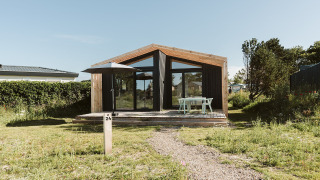 Et moderne naturhus med store glasvinduer og træterrasse på Holiday park De Klepperstee i Nederlandene.