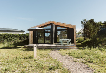 Een modern natuurhuisje met grote ramen en houten terras op vakantiepark De Klepperstee in Nederland.