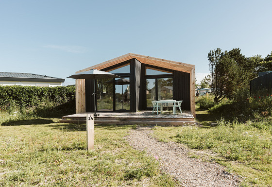 A modern nature house with large glass windows and wooden deck at Holiday park De Klepperstee, Netherlands.