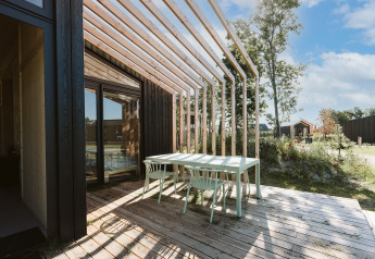 Buitenterras bij Nature house Barn op Holiday park De Klepperstee, Nederland, met houten tafel en stoelen